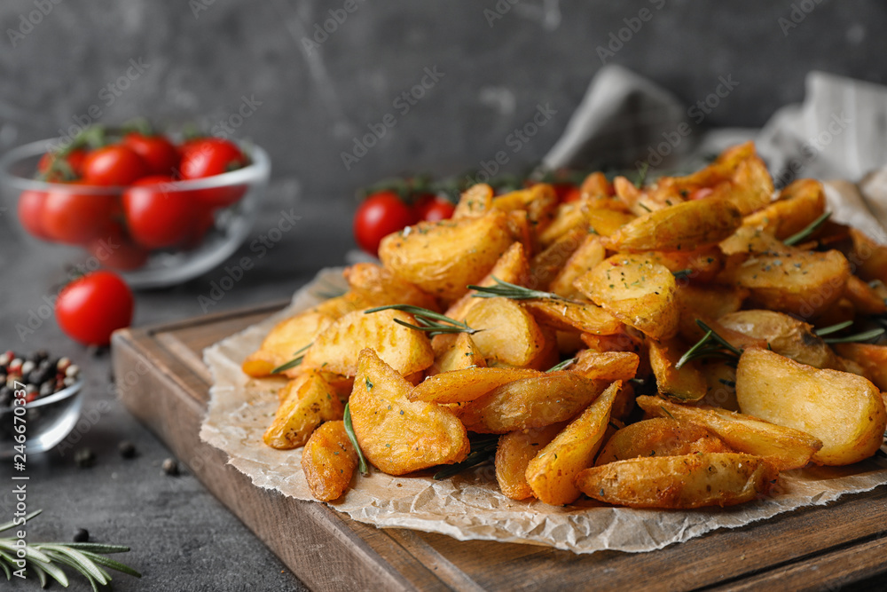 Wooden board with baked potatoes and rosemary on table Wooden board with baked potatoes and rosemary on table