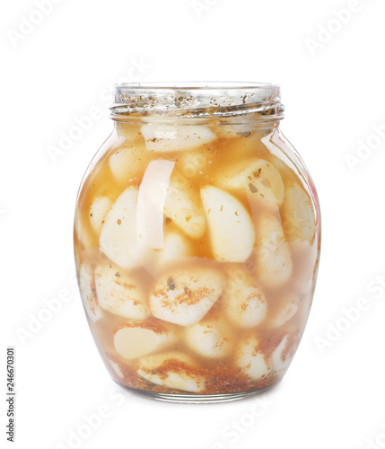 Glass jar with preserved garlic on white background