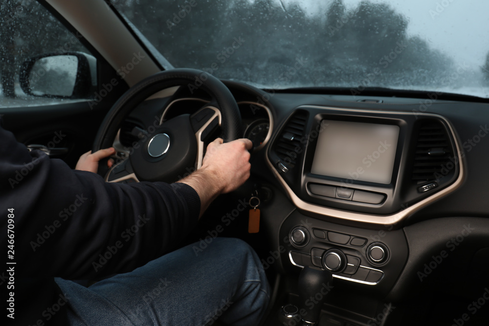 Young man driving car along winter forest, closeup