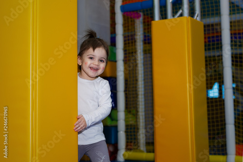 Photography Little toddler girl look out of yellow column in playroom