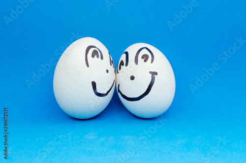Two white eggs smile at each other. Painted faces and emotions
