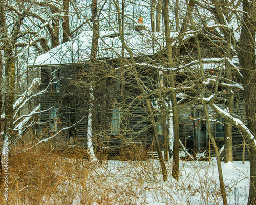 snowy dilapidated abandoned house surrounded by trees