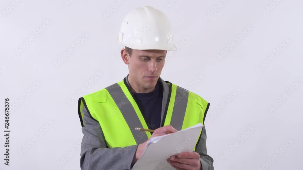 Portrait of builder in uniform writing on paper and giving orders close up. Shooting in the studio on a white background. Portrait of builder in uniform writing on paper and giving orders close up. Shooting in the studio on a white background.