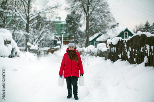 Fototapeta Naklejka Na Ścianę i Meble -  Woman on the street in the Russian village at snowy winter.