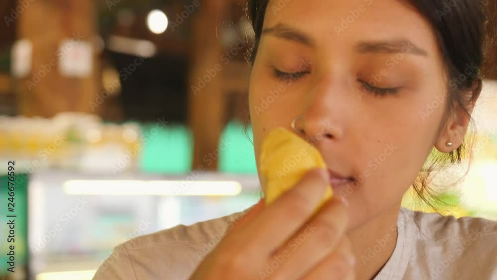 Young Tourist Woman Eating Durian First Time. Female Holding Piece of Durian Pulp and Sniffing It Enjoying Good Sweet Taste. 4K Slowmotion. Kuala Lumpur, Malaysia. Young Tourist Woman Eating Durian First Time. Female Holding Piece of Durian Pulp and Sniffing It Enjoying Good Sweet Taste. 4K Slowmotion. Kuala Lumpur, Malaysia.