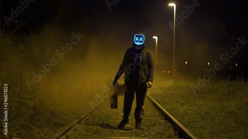 Man with glowing purge mask is holding a lantern with yellow smoke in slow motion. photo