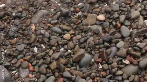 Stones on the beach are moved by waves on shore. photo