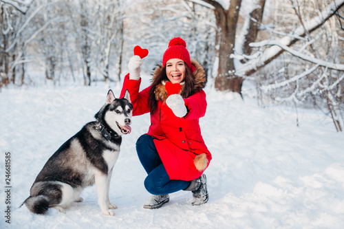 Young girl with her husky dog in winter park. Domestic pet. Husky