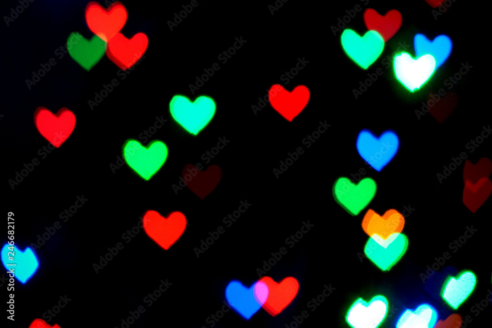 Multi colored blurred lights in the shape of hearts in the dark.