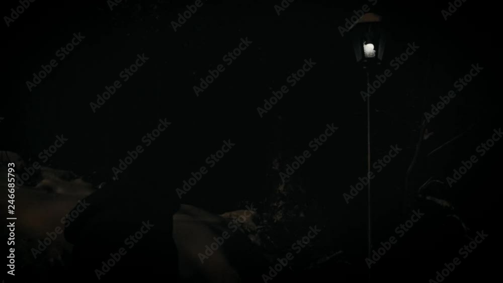 Mysterious young man looks at the broken flashing street lamp.. Horror scene. Natural street light