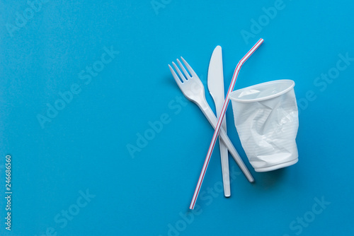 White single-use plastic and plastic drink straws on a blue background. Say no to single use plastic. Environmental, pollution concept. photo