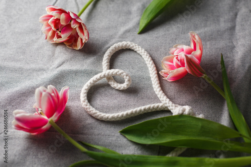 Heart from rope and bouquet of tulips on a gray background with space for text