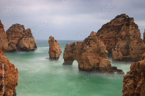 Sunrise over the ocean, the pillars and arch of rock standing in the water at Lagos, Algarve, Portugal. Long exposure showing the movement and the vibrant colors at this tourist attraction. photo