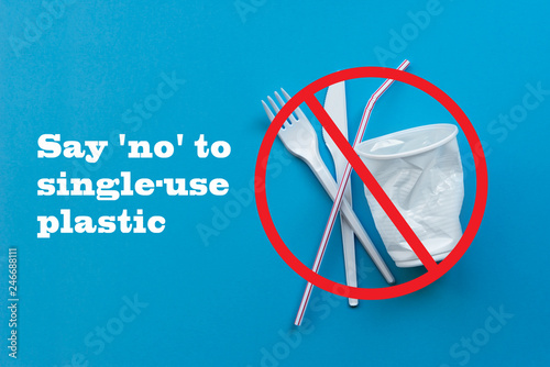 White single-use plastic and plastic drink straws on a blue background. Say no to single use plastic. Environmental, pollution concept. photo