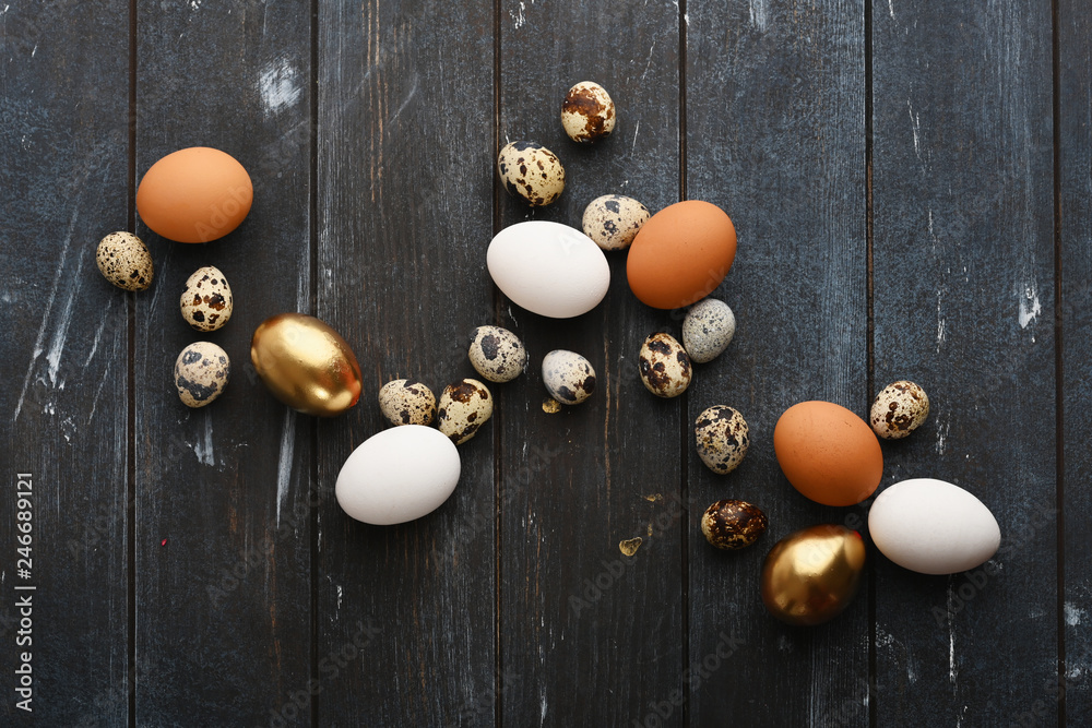 Naklejka premium Different size quail and chicken eggs on a wooden surface. Horizontal.