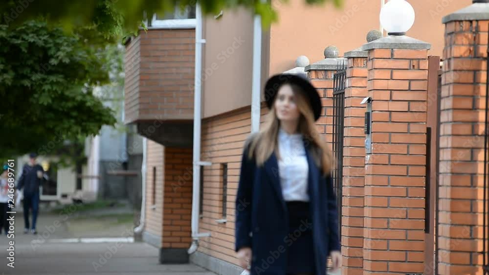 young woman in a hat walking down the street in spring young woman in a hat walking down the street in spring
