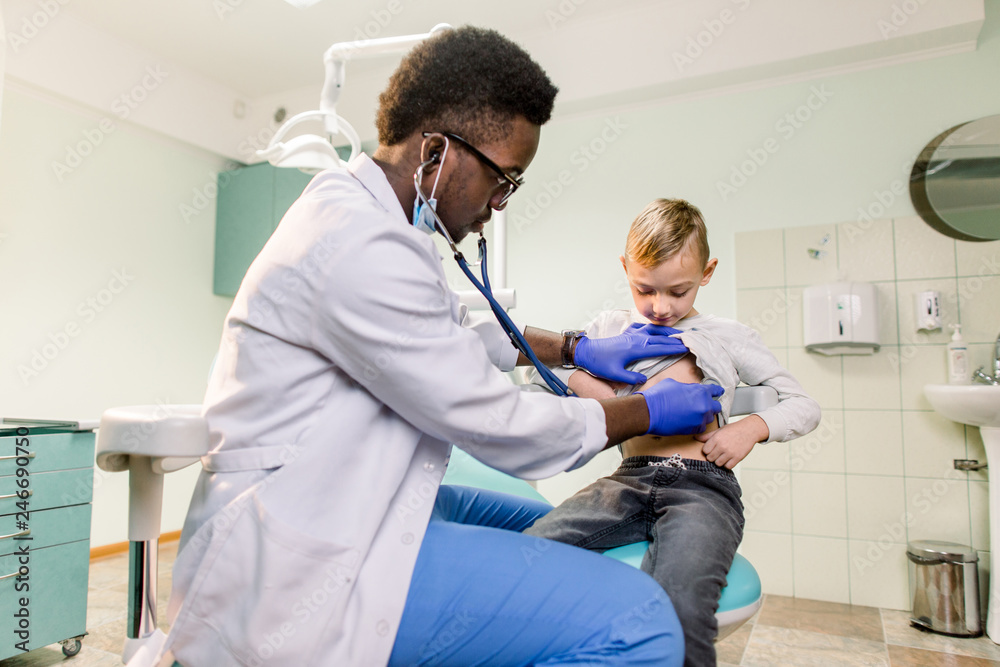 Obraz premium African American Doctor and child patient. Physician examines little boy by stethoscope. Medicine and children's therapy concept