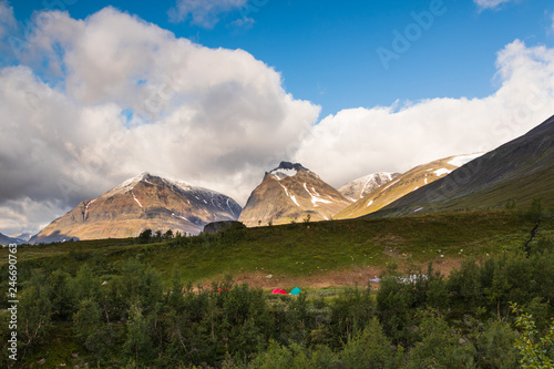 Couple of tents camping below a mountain range  with Toulpagorni mountain in the middle. Photographed while walking the Kungsleden  Kings path  hike close to tarfala. 