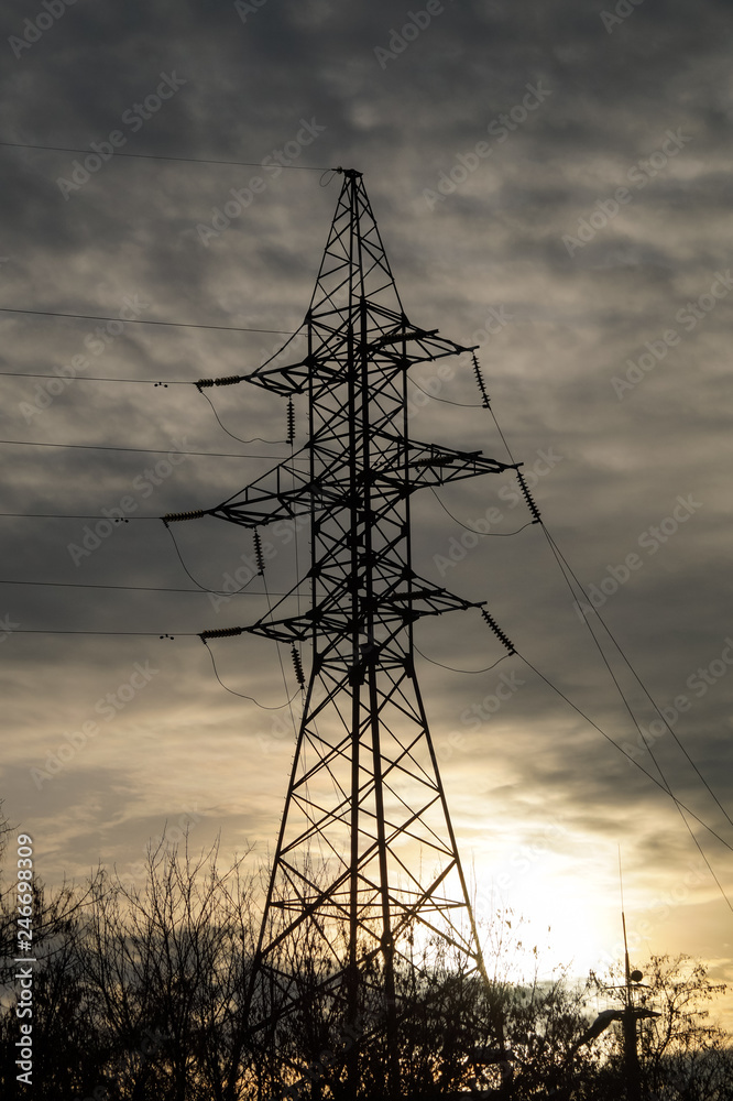 Electric pole made of metal for high-voltage wires at sunset.
