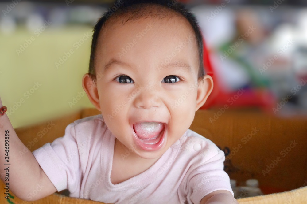 Happy Asian baby girl is smiling and laughing. She practice to standing in the paper box. 