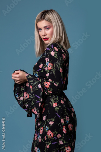 Young blonde woman in floral summer dress on a blue background