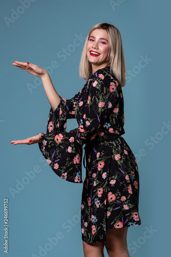 Image of pretty blonde woman in spring dress showing something big with hands