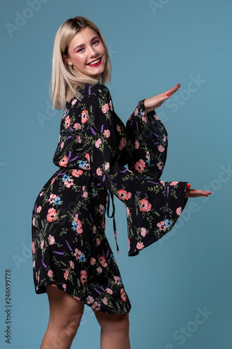 Image of pretty blonde woman in spring dress showing something big with hands