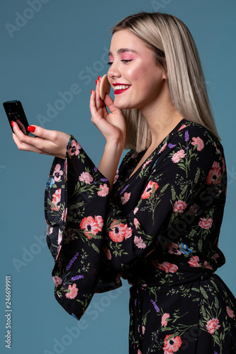 Pretty young woman face powder applying makep
