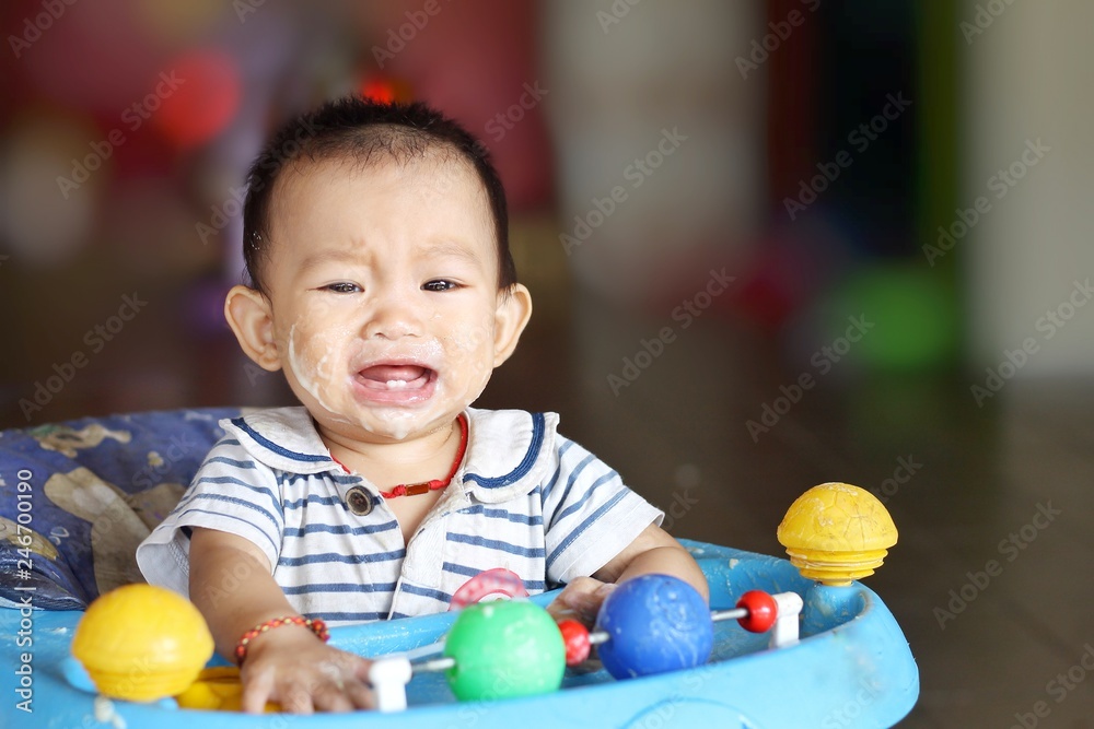 Fototapeta premium Emotion of baby concept, alone child girl sad and crying in a baby chair. Her face dirty and messy by food. 