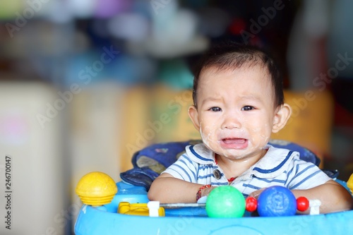Emotion of baby concept, alone child girl sad and crying in a baby chair. Her face dirty and messy by food. 