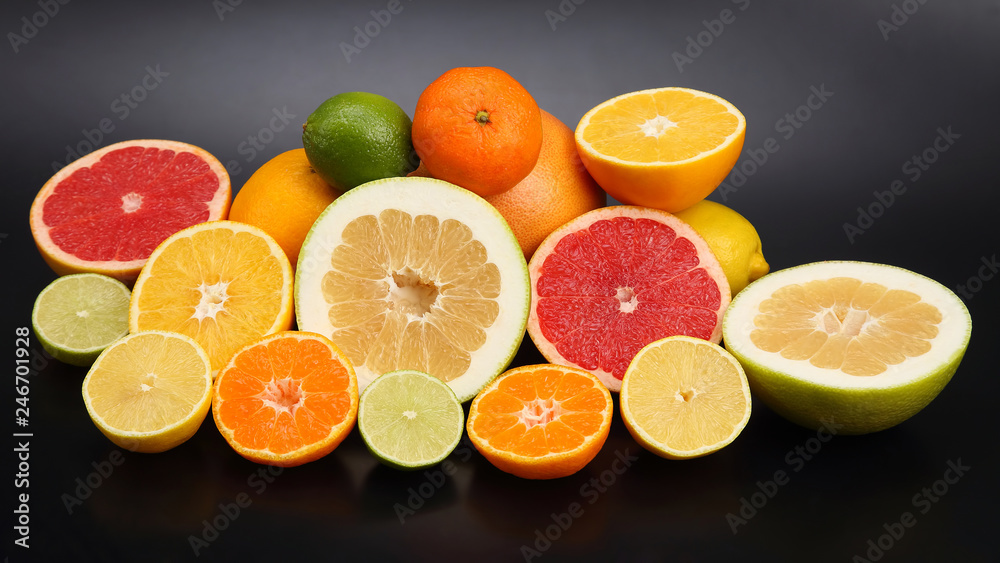 cut pieces of different citrus fruits on dark background cut pieces of different citrus fruits on dark background