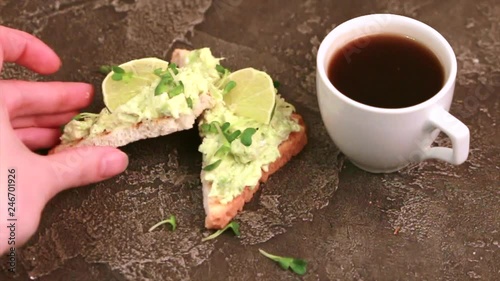 Toasts with avocado pate, fresh microgreen and cup of coffee on dark concrete background. Healthy and tasty breakfast