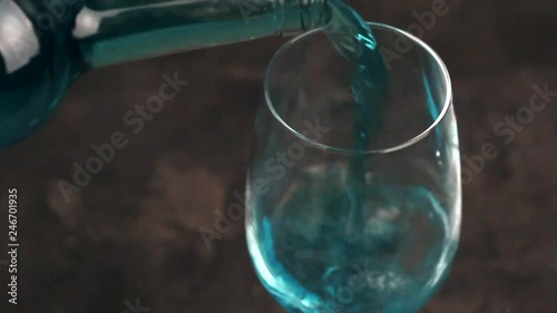 Glass and bottle of trendy blue wine. Spanish blue wine chardonnay on dark concrete background. Romantic date
