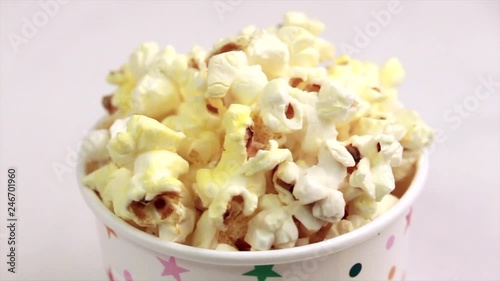 Tasty salty popcorn in paper cup on light marble background. Pastime watching movies. Cinema snacks