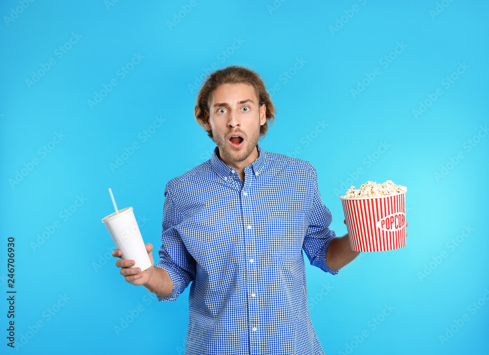 Naklejka premium Emotional man with popcorn and beverage during cinema show on color background