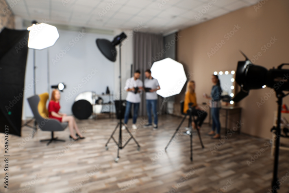 Blurred photo studio with professional equipment and team of workers