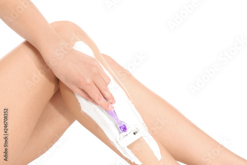 Beautiful young woman shaving leg on white background  closeup view