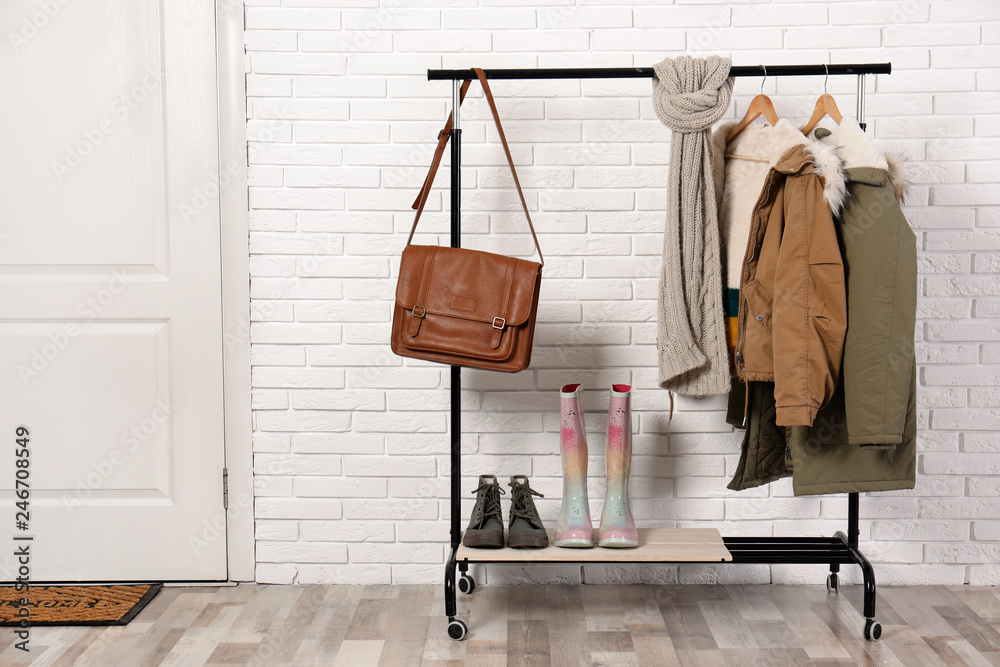 Stylish hallway interior with shoes and clothes on hanger stand