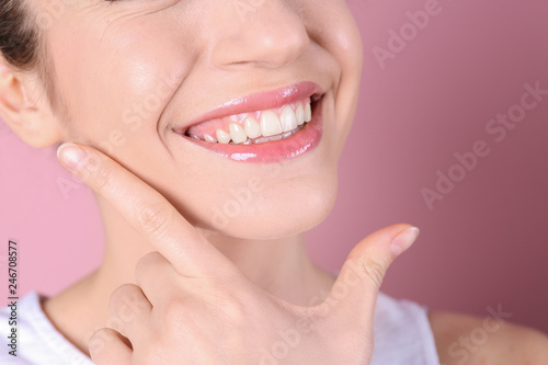 Young woman with healthy teeth and beautiful smile on color background, closeup