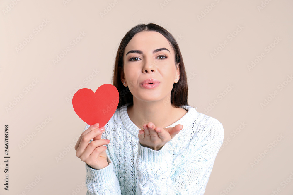 Portrait of young woman with paper heart on color background Portrait of young woman with paper heart on color background