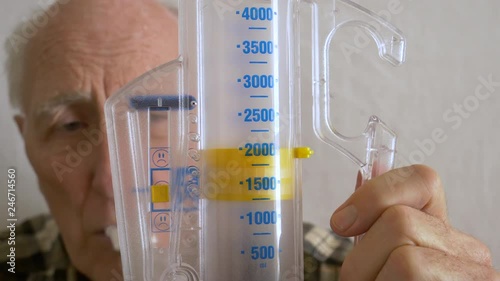 Aging senior practices breathing with incentive spirometer device-Closeup photo