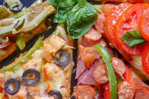 Pizza with ham, orange and red pepper, cherry tomatoes, black olives, mushrooms and fresh basil. Italian pizza. Symbolic image. Concept for a tasty and healthy meal. Selective focus. Close up.