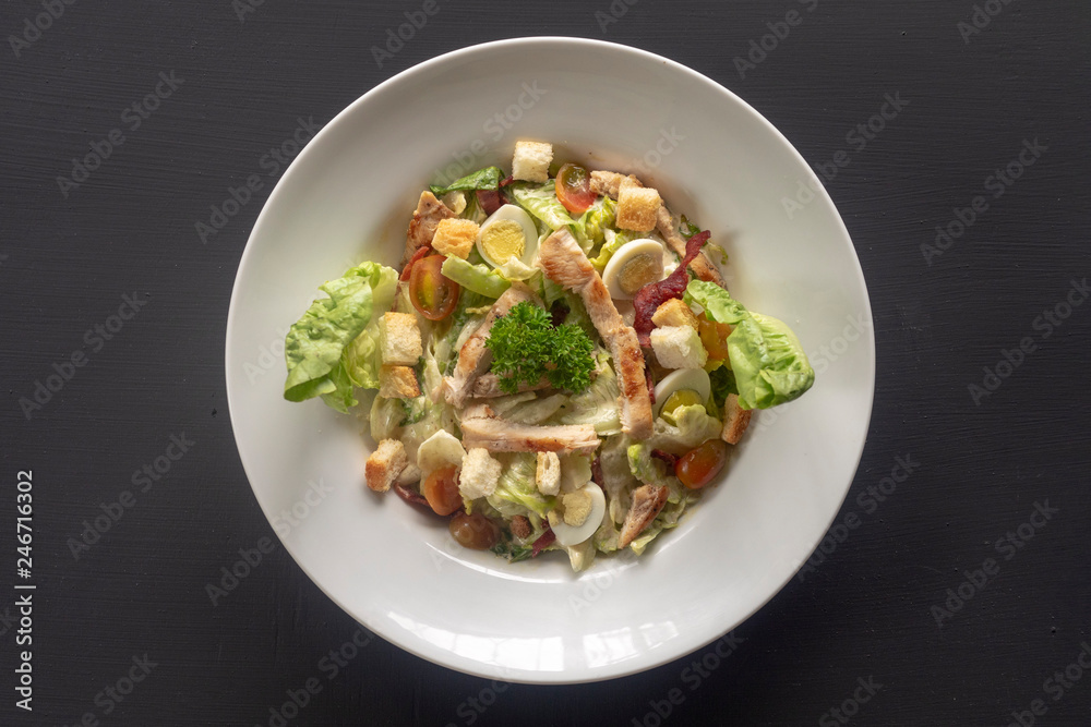 Caesar salad on a white plate on a dark background.