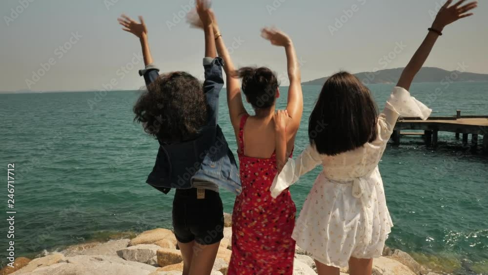 Group of friends standing on the coast and looking at the sea Group of friends standing on the coast and looking at the sea