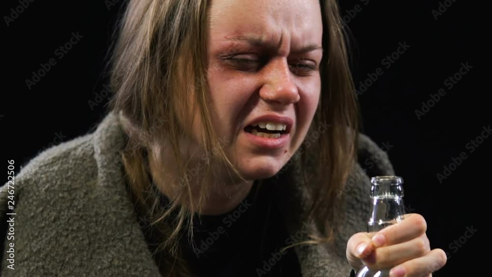 Stressed woman drinking vodka crying for resentment and grief, hopelessness