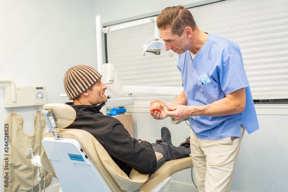 Dentist explains to patient on teeth mockup Dentist explains to patient on teeth mockup