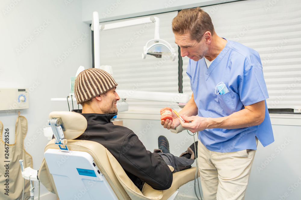 Dentist explains to patient on teeth mockup Dentist explains to patient on teeth mockup