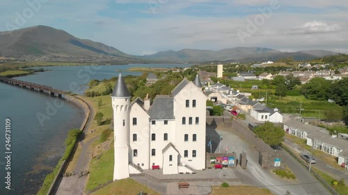 Fantasy castle in foreground set beside river and mountain range in background photo