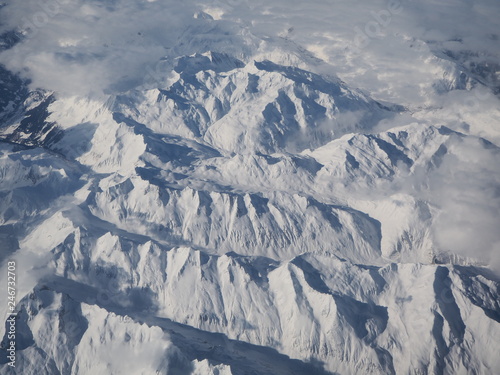 Aerial landscape of the Alps in Europe during winter season with fresh snow. View from the window of the airplane