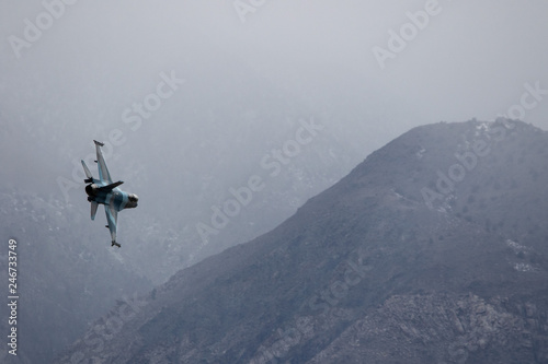 Fighter jet maneuvering in a hazy winter sky